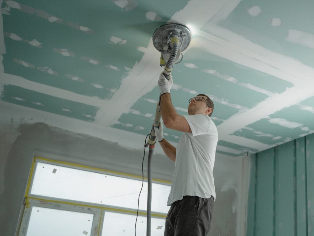 pexels photo 6474343 A professional worker sanding the ceiling during a home renovation project. Indoor construction setting.