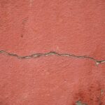 High-resolution image of a cracked red-painted concrete wall surface for texture background.