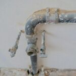 Close-up of exposed plumbing pipes with rustic textures on a construction site wall.