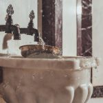 Elegant marble washbasin with water flowing from ornate faucet, showcasing luxury and hygiene.