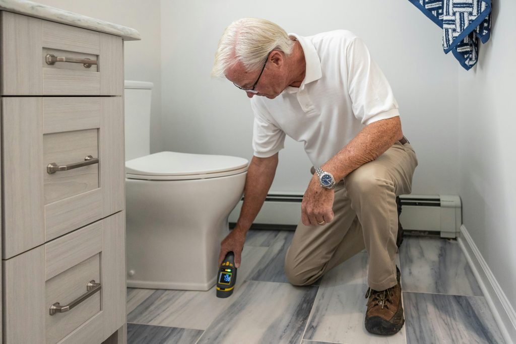 pexels photo 32497162 32497162 A senior man using a device to inspect a bathroom for maintenance or repair.