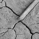 A detailed black and white image of cracked, dry earth with a distinct pattern.