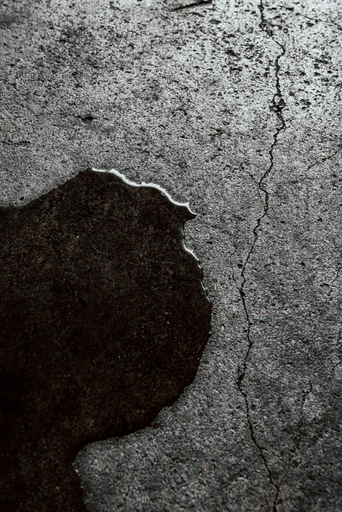 pexels photo 5214204 5214204 Detailed image of a wet cracked concrete surface with visible texture.